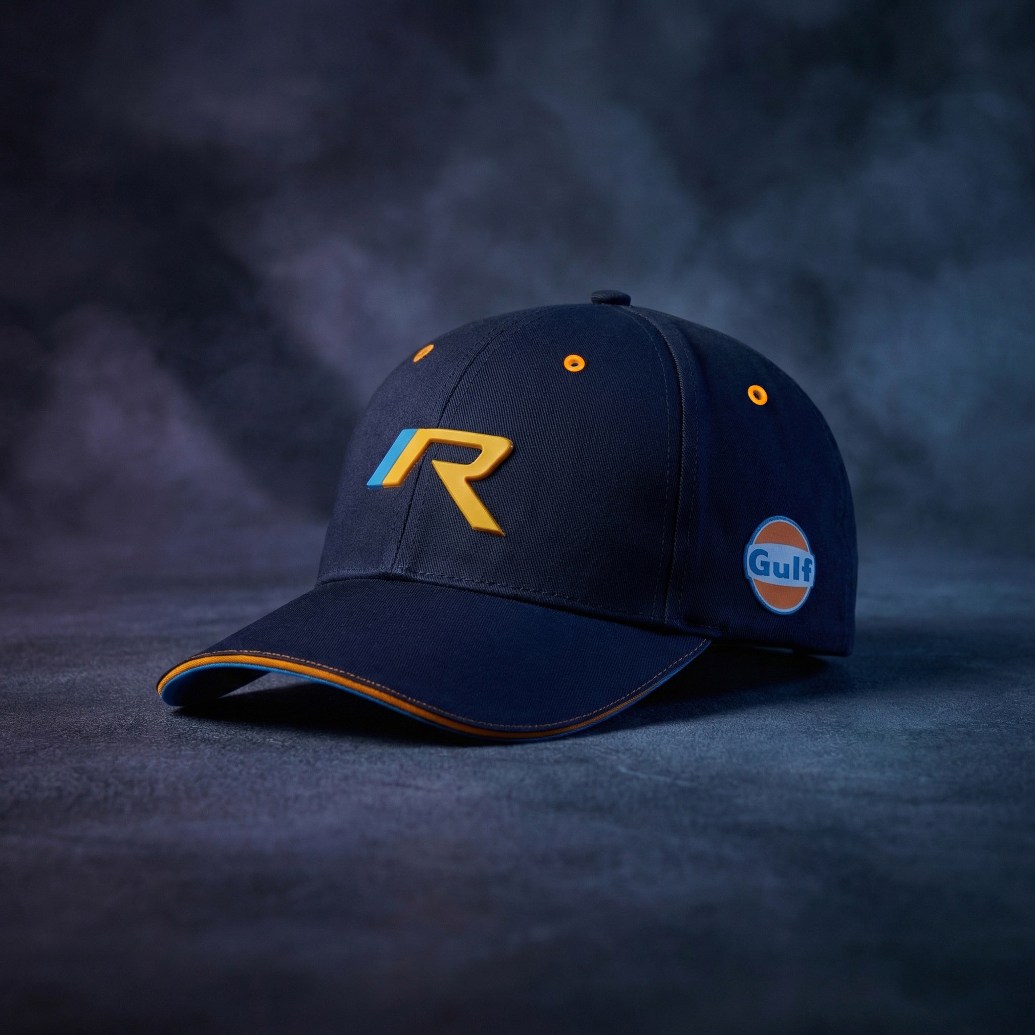 Bespoke navy six-panel R / Gulf cap with steel eyelets and a colour-contrast sandwich peak, studio lit